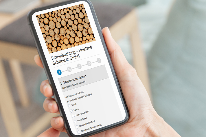 Person hält ein Smartphone in der Hand, auf dem Bildschirm ist deutlich ein Terminbuchungsprogramm zu sehen.